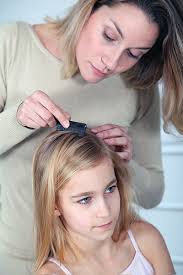An adult checking a kids head for lice